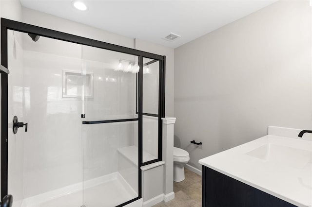 bathroom with toilet, a sink, a shower stall, baseboards, and visible vents