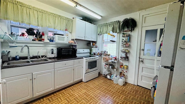 kitchen featuring light parquet floors, white appliances, white cabinetry, and sink