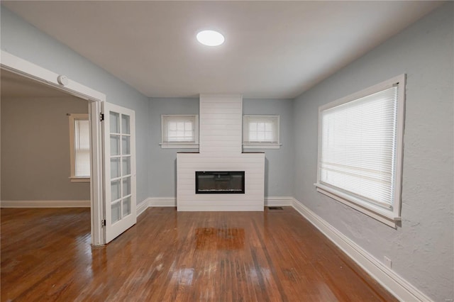 unfurnished living room with a fireplace and dark wood-type flooring