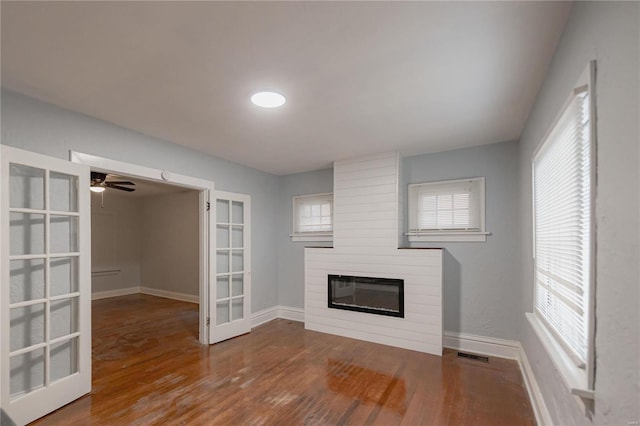 unfurnished living room with hardwood / wood-style floors, a large fireplace, and ceiling fan