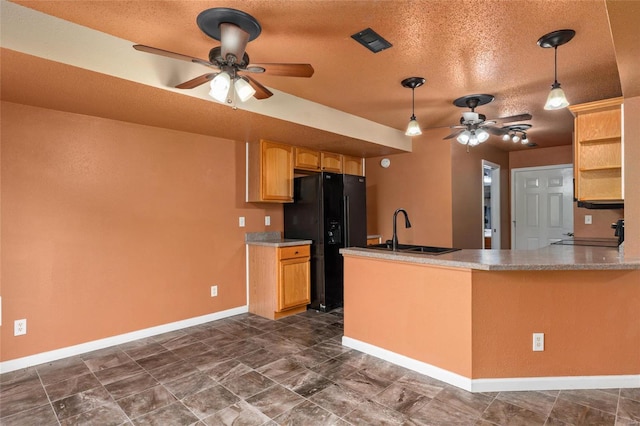 kitchen with a textured ceiling, black refrigerator with ice dispenser, light brown cabinetry, ceiling fan, and sink