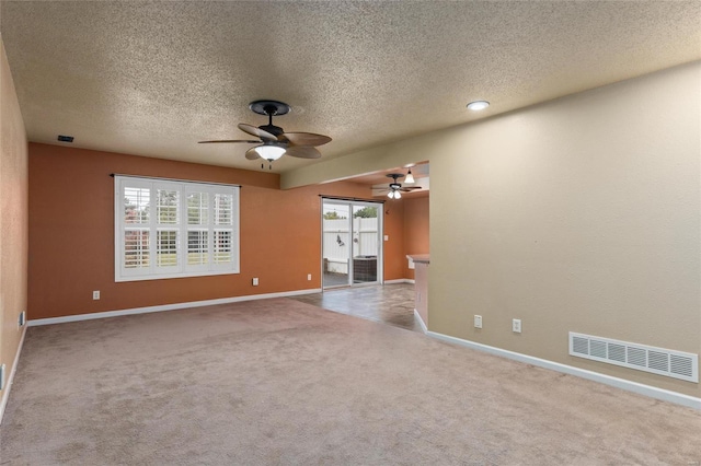 empty room featuring a textured ceiling, light carpet, and ceiling fan