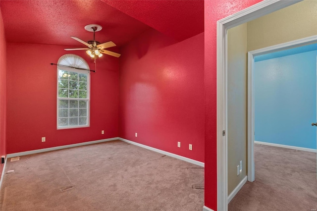 spare room featuring a textured ceiling, carpet, and ceiling fan