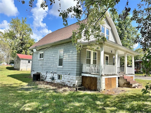 view of side of property featuring a yard, covered porch, and central AC