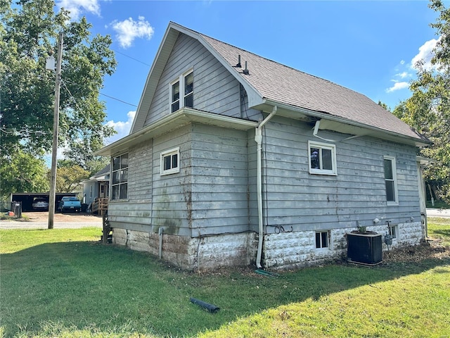 view of side of property featuring cooling unit and a yard