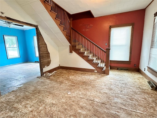 unfurnished living room featuring ceiling fan and carpet