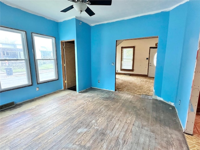 unfurnished bedroom featuring multiple windows, hardwood / wood-style floors, and ceiling fan