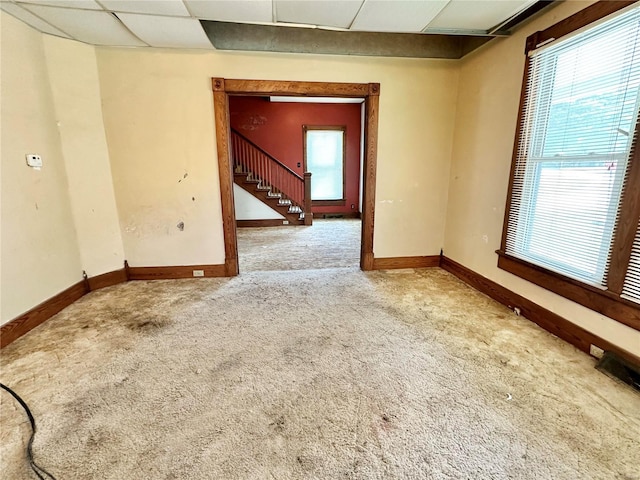 empty room with a drop ceiling and carpet floors