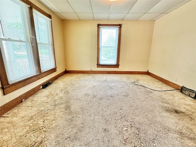 empty room featuring carpet floors and a paneled ceiling