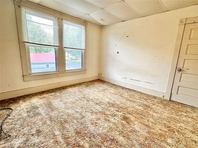 carpeted spare room with a drop ceiling