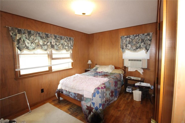 bedroom featuring cooling unit, wooden walls, and dark wood-type flooring