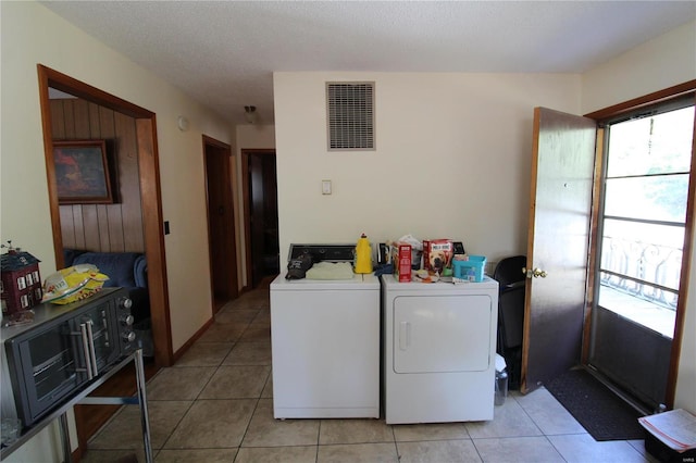 laundry area with a textured ceiling, independent washer and dryer, and light tile patterned floors