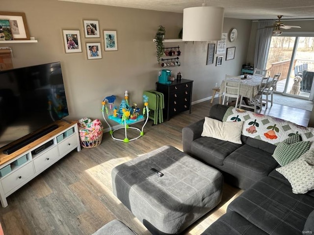 living area featuring wood finished floors, a ceiling fan, and baseboards