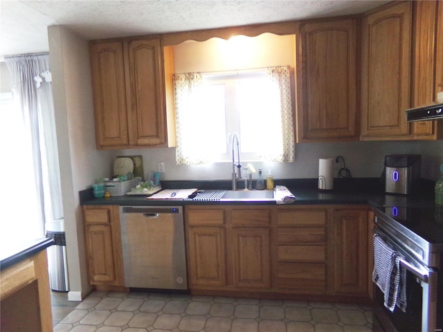 kitchen with a textured ceiling, stainless steel appliances, a sink, ventilation hood, and brown cabinetry