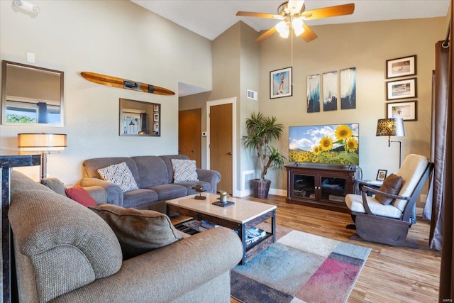 living room with lofted ceiling, ceiling fan, and light hardwood / wood-style floors