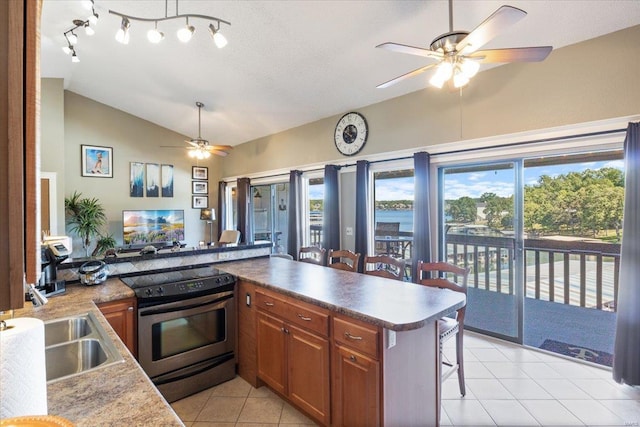 kitchen with vaulted ceiling, a kitchen breakfast bar, light tile patterned floors, stainless steel range with electric stovetop, and ceiling fan