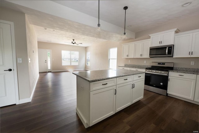 kitchen featuring pendant lighting, appliances with stainless steel finishes, dark wood-type flooring, and white cabinets