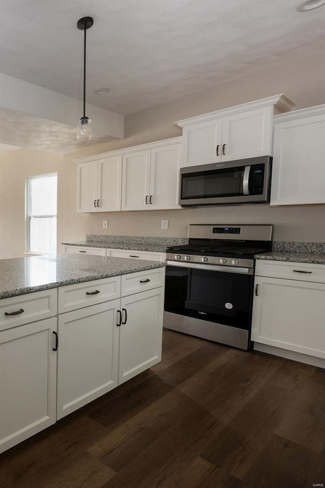 kitchen featuring decorative light fixtures, appliances with stainless steel finishes, dark wood-type flooring, and light stone countertops