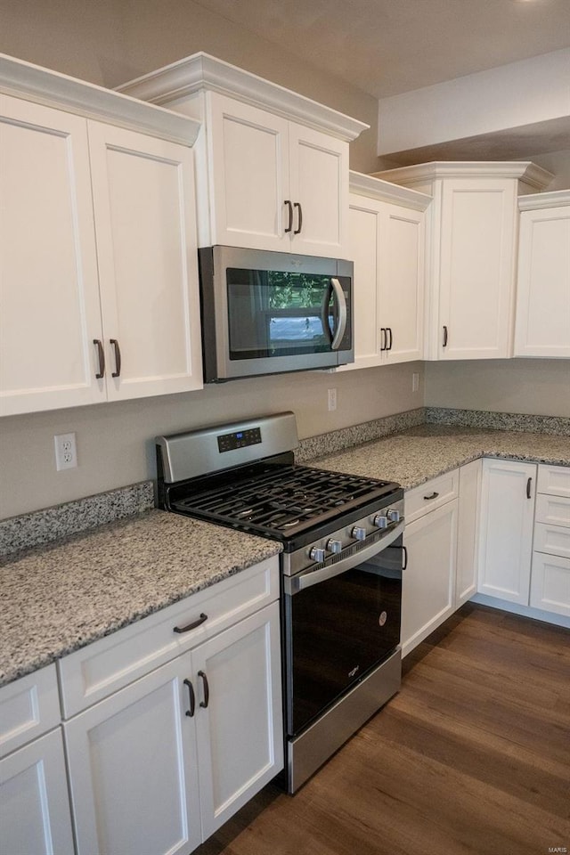 kitchen featuring stainless steel appliances, white cabinetry, and dark wood-type flooring