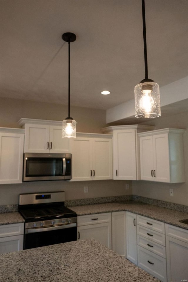 kitchen with white cabinets, stainless steel appliances, and hanging light fixtures