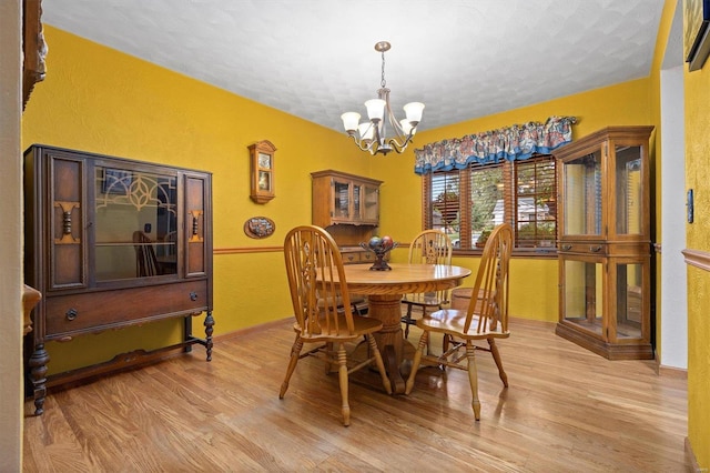 dining space with light wood-type flooring and a chandelier