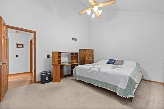 carpeted bedroom with ceiling fan and high vaulted ceiling