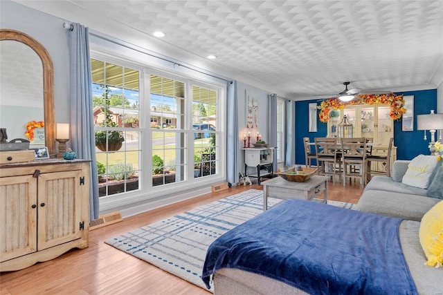 living room featuring ornamental molding, ceiling fan, and light hardwood / wood-style flooring