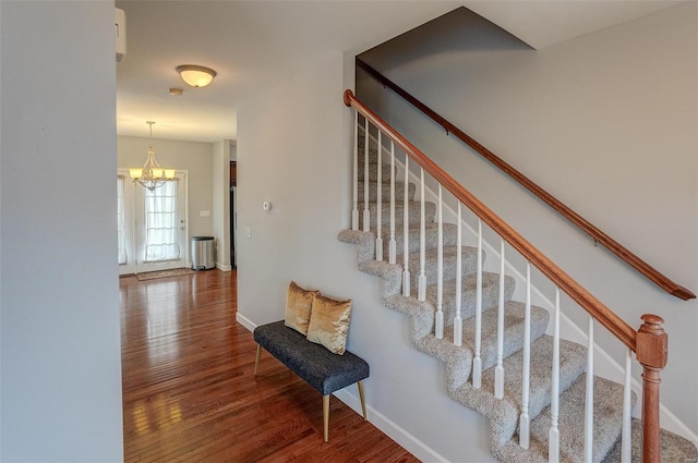 staircase featuring hardwood / wood-style flooring and a notable chandelier