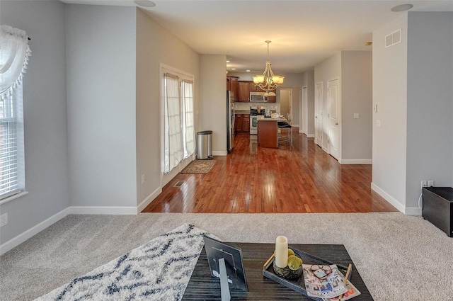 kitchen featuring hanging light fixtures, appliances with stainless steel finishes, a kitchen island, dark hardwood / wood-style flooring, and a chandelier