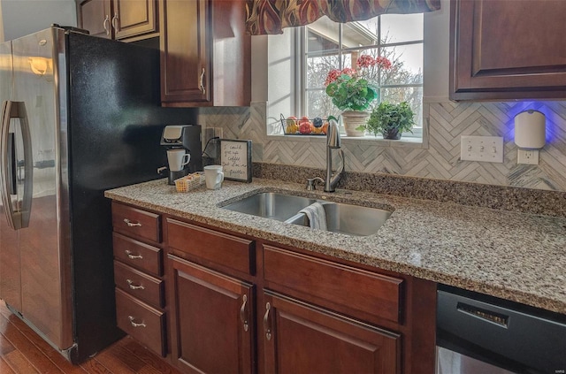 kitchen featuring light stone countertops, sink, stainless steel appliances, dark hardwood / wood-style floors, and decorative backsplash