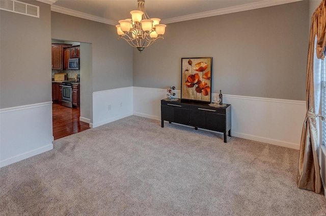 carpeted empty room featuring crown molding and a chandelier