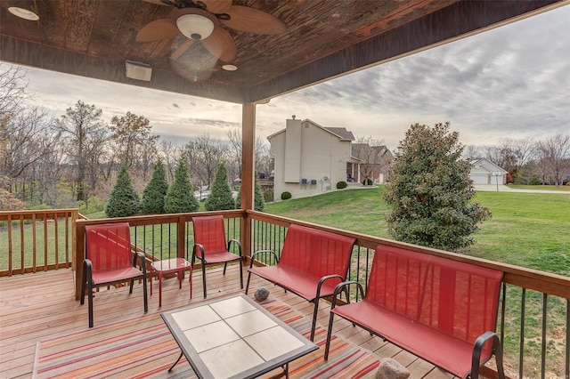 wooden deck featuring a lawn and ceiling fan