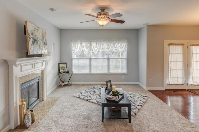 living room featuring a high end fireplace, wood-type flooring, a wealth of natural light, and ceiling fan