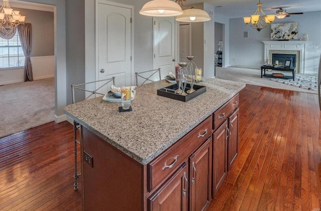 kitchen featuring pendant lighting, dark hardwood / wood-style flooring, a kitchen island, and a breakfast bar area