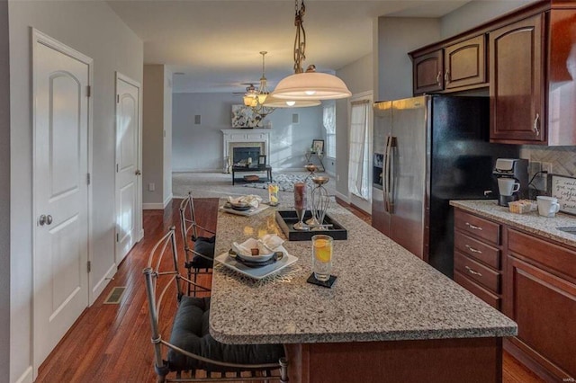 kitchen with a kitchen breakfast bar, a center island, dark hardwood / wood-style floors, and tasteful backsplash