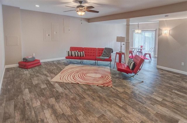 living room featuring wood-type flooring, ceiling fan with notable chandelier, and ornate columns