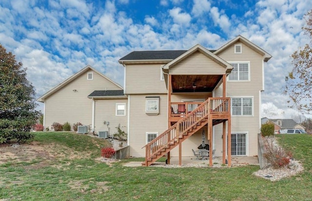 rear view of property with a lawn, a wooden deck, and central AC unit