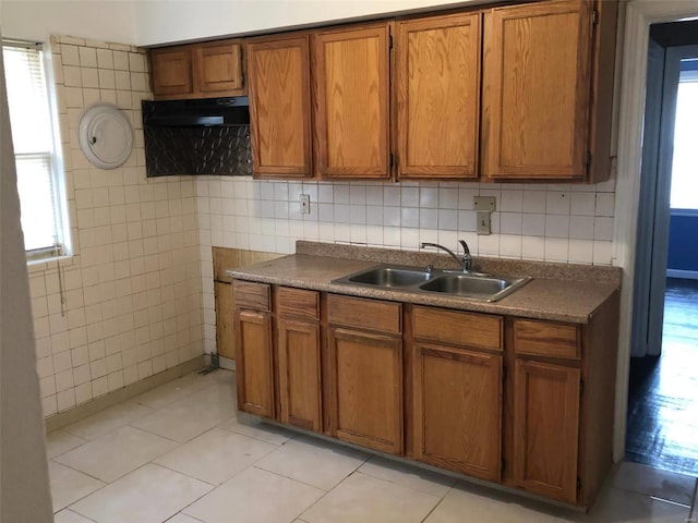 kitchen with tile walls, decorative backsplash, sink, and light tile patterned floors