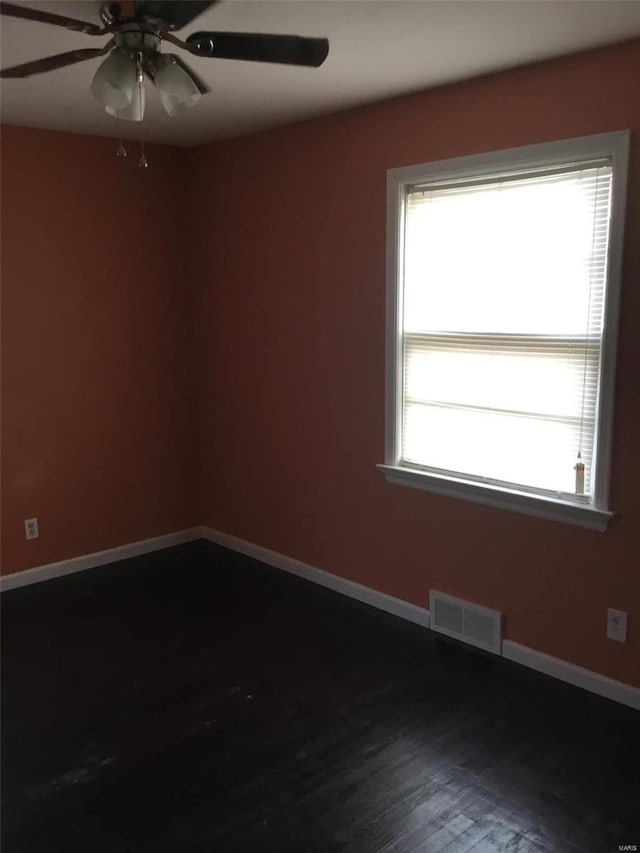 spare room with a wealth of natural light, ceiling fan, and dark hardwood / wood-style flooring