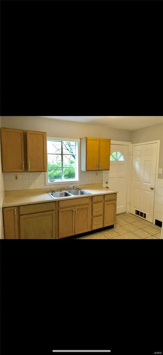 kitchen featuring light tile patterned floors, tasteful backsplash, and sink