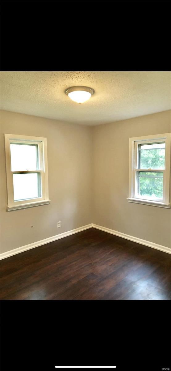 empty room with a textured ceiling and dark hardwood / wood-style floors