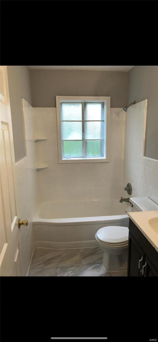 full bathroom with vanity, tile walls, tiled shower / bath combo, and toilet