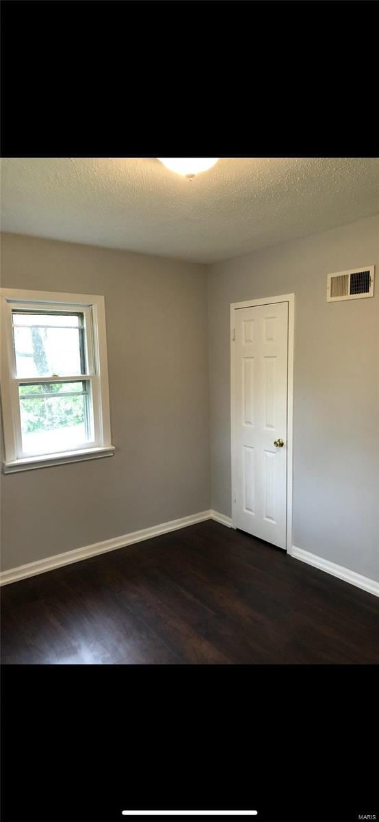 unfurnished room featuring a textured ceiling and dark wood-type flooring