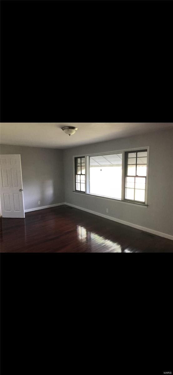 spare room with dark hardwood / wood-style floors and a healthy amount of sunlight