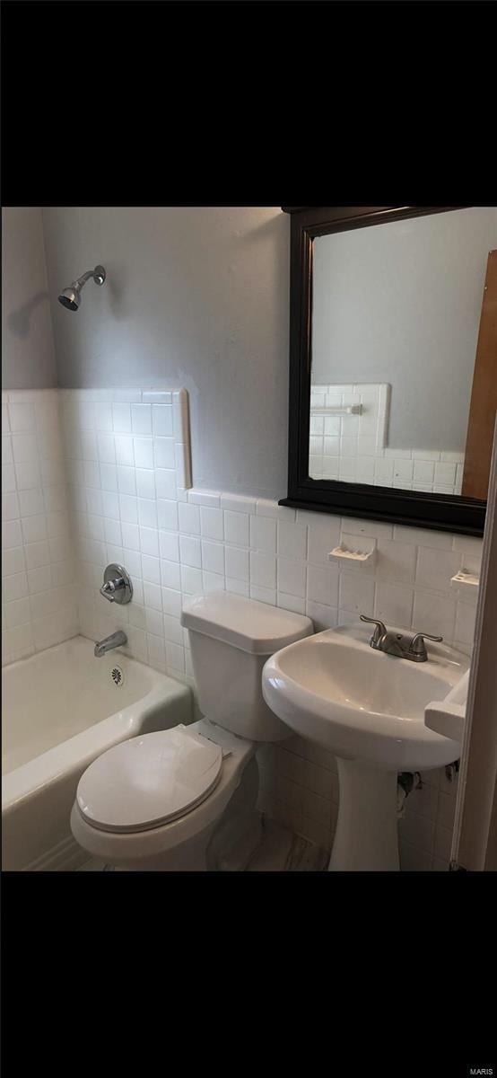 bathroom featuring tile walls, tiled shower / bath combo, and toilet