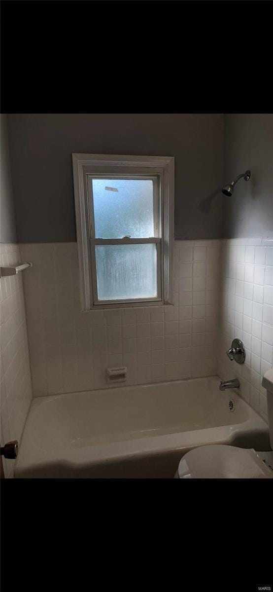 bathroom with tiled shower / bath, tile walls, and toilet