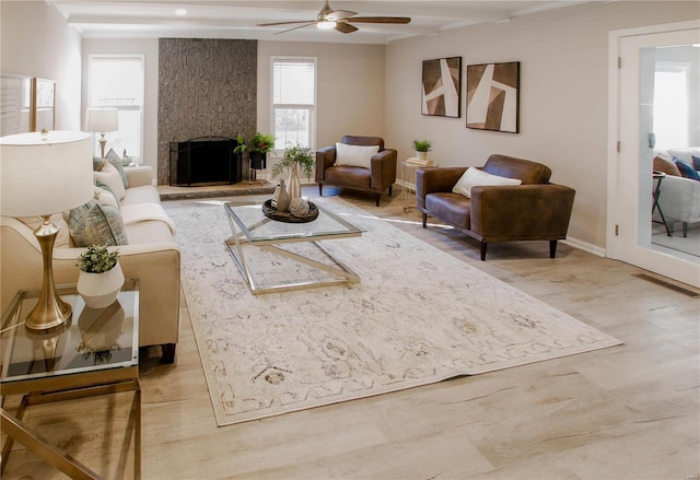 living room with hardwood / wood-style flooring, a stone fireplace, and ceiling fan