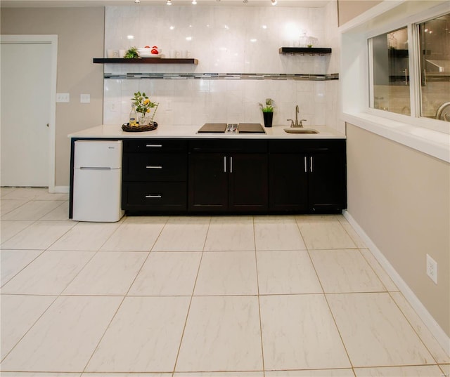 kitchen with black electric stovetop, tasteful backsplash, sink, white fridge, and light tile patterned flooring