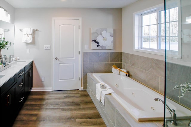 bathroom with vanity, hardwood / wood-style flooring, and a relaxing tiled tub