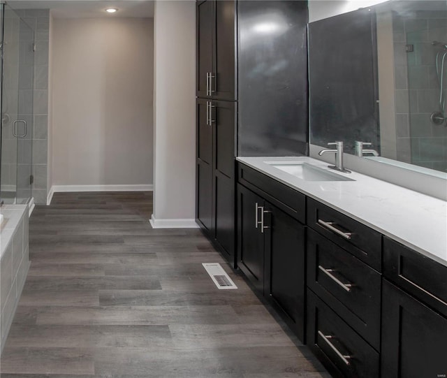 bathroom with hardwood / wood-style floors, vanity, and an enclosed shower